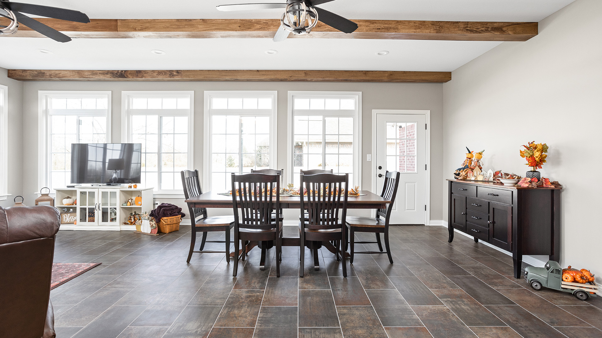 open concept living and dining room with exposed wood beams and large windows by Gannon and Company
