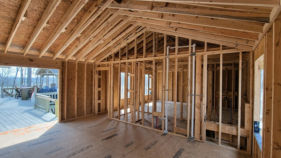 home addition framing in progress with exposed wood studs and open floor plan by Gannon and Company